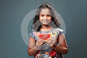 A little girl holds a slice of watermelon