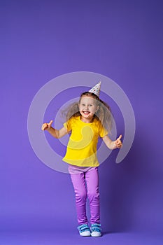 Little girl in holiday hat with a happy face is happy, jumps and shows class