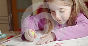 Little girl at home doing homework drawing on school`s book