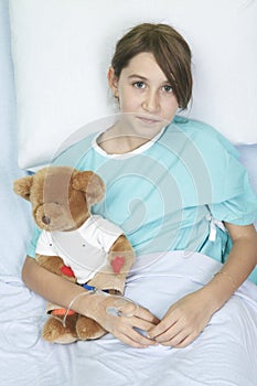 Little girl in hospital bed with teddy bear