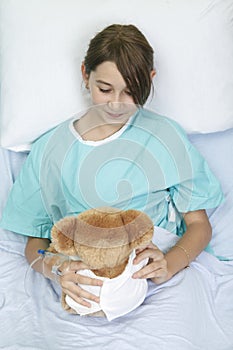 Little girl in hospital bed with teddy bear