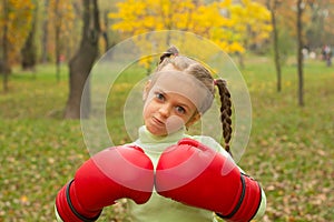 A little girl in huge boxing gloves makes an evil face.