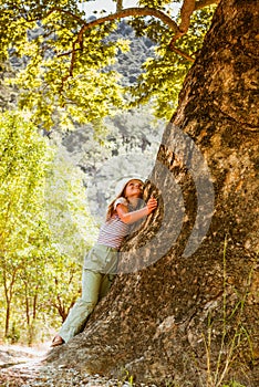 Little girl hugging big tree