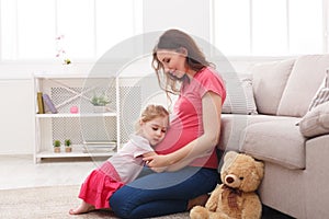 Little girl hugging her pregnant mother belly