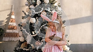 Little Girl Hugging Little Rabbit near Xmas Tree