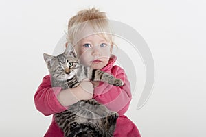 Little girl hugging pet kitten