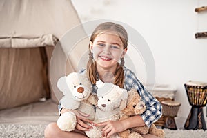 Little girl hugging plush teddies and smiling