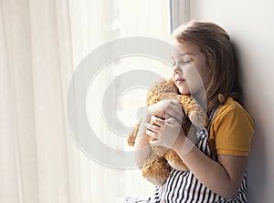 Little girl hugs plush toy empty space background. Friendship and relationship. Caucasian kid dreaming with closed eyes. Emotional