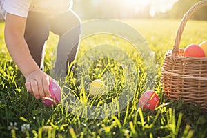 Little girl hunts Easter egg. Child putting colorful eggs in a basket