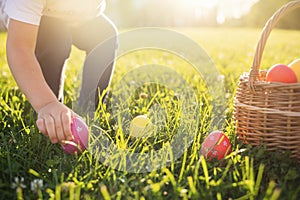 Little girl hunts Easter egg. Child putting colorful eggs in a basket photo