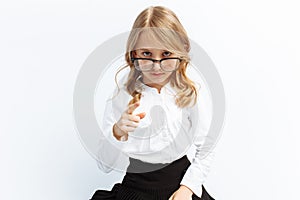 Little girl in the image of a strict teacher, glasses, isolated background, serious look, funny and cute