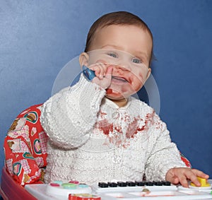 The little girl independently eats with a spoon