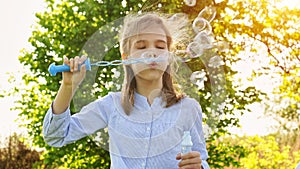 Little girl inflate soap bubbles on a picnic