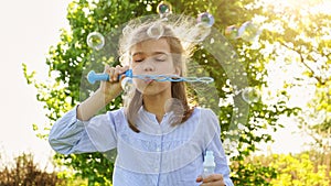 Little girl inflate soap bubbles on a picnic