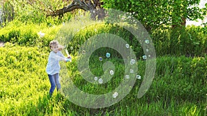 Little girl inflate soap bubbles on a picnic