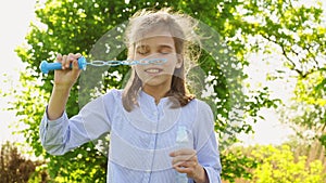 Little girl inflate soap bubbles on a picnic