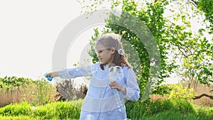 Little girl inflate soap bubbles on a picnic