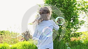 Little girl inflate soap bubbles on a picnic