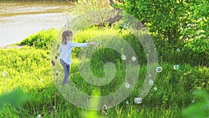 Little girl inflate soap bubbles on a picnic