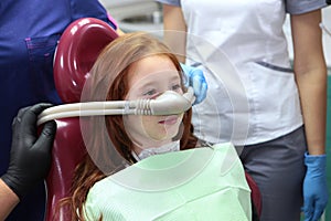 A little girl is injected with an inhalation sedative during dental treatment at a dental clinic. Dental treatment for a