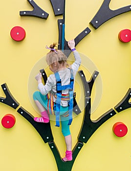 Little girl in insurance trains on climbing wall