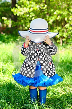 little girl in jacket and boots in park covered