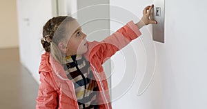 Little girl in a jacket presses the elevator button