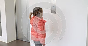 Little girl in a jacket presses the elevator button