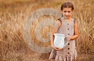 Little girl with jar of milk in the counrtyside