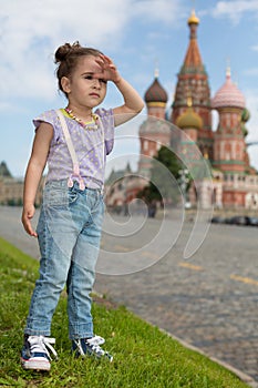 Little girl in jeans with suspenders near the Saint Basils Cathedral photo