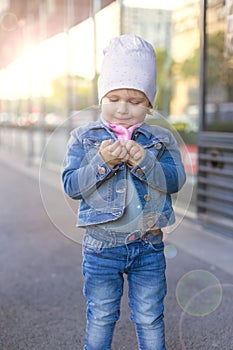 A little girl in jeans wear shows on the street