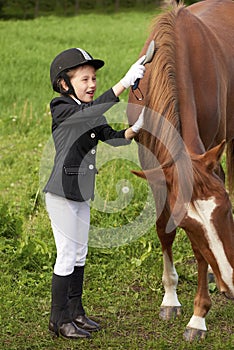 Little girl jockey attend and brushing her horse