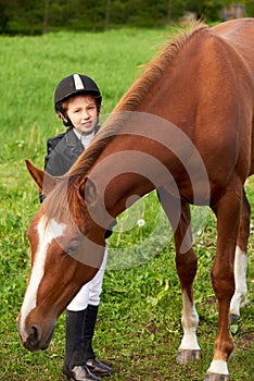 Little girl jockey attend and brushing her horse