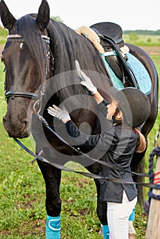 Little girl jockey attend and brushing her horse