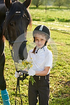 Little girl jockey communicating with her horses in professional outfit