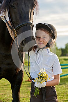 Little girl jockey communicating with her horses in professional outfit