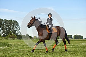 little girl jockey riding a horse across country in professional outfit