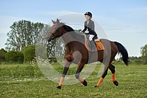 Little girl jockey riding a horse across country in professional outfit