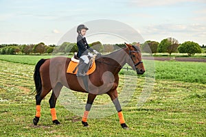 Little girl jockey riding a horse across country in professional outfit