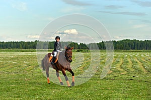 Little girl jockey riding a horse across country in professional outfit