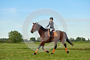 Little girl jockey riding a horse across country in professional outfit