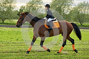 Little girl jockey riding a horse across country in professional outfit