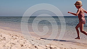 A little girl joyfully runs along the sea on the sand on the shore of Red Sea