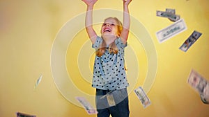 Little girl joyfully tossing money into the air. Happy child throwing cash up in the air.