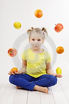 Little girl juggling with fruits