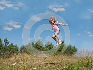 A little girl jumping against the blue sky background