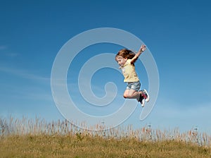 A little girl jumping against the blue sky background