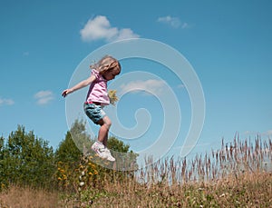 A little girl jumping against the blue sky background