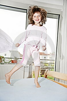 Little girl jumping on a bed