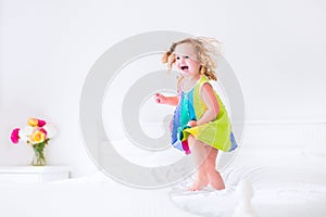 Little girl jumping on a bed